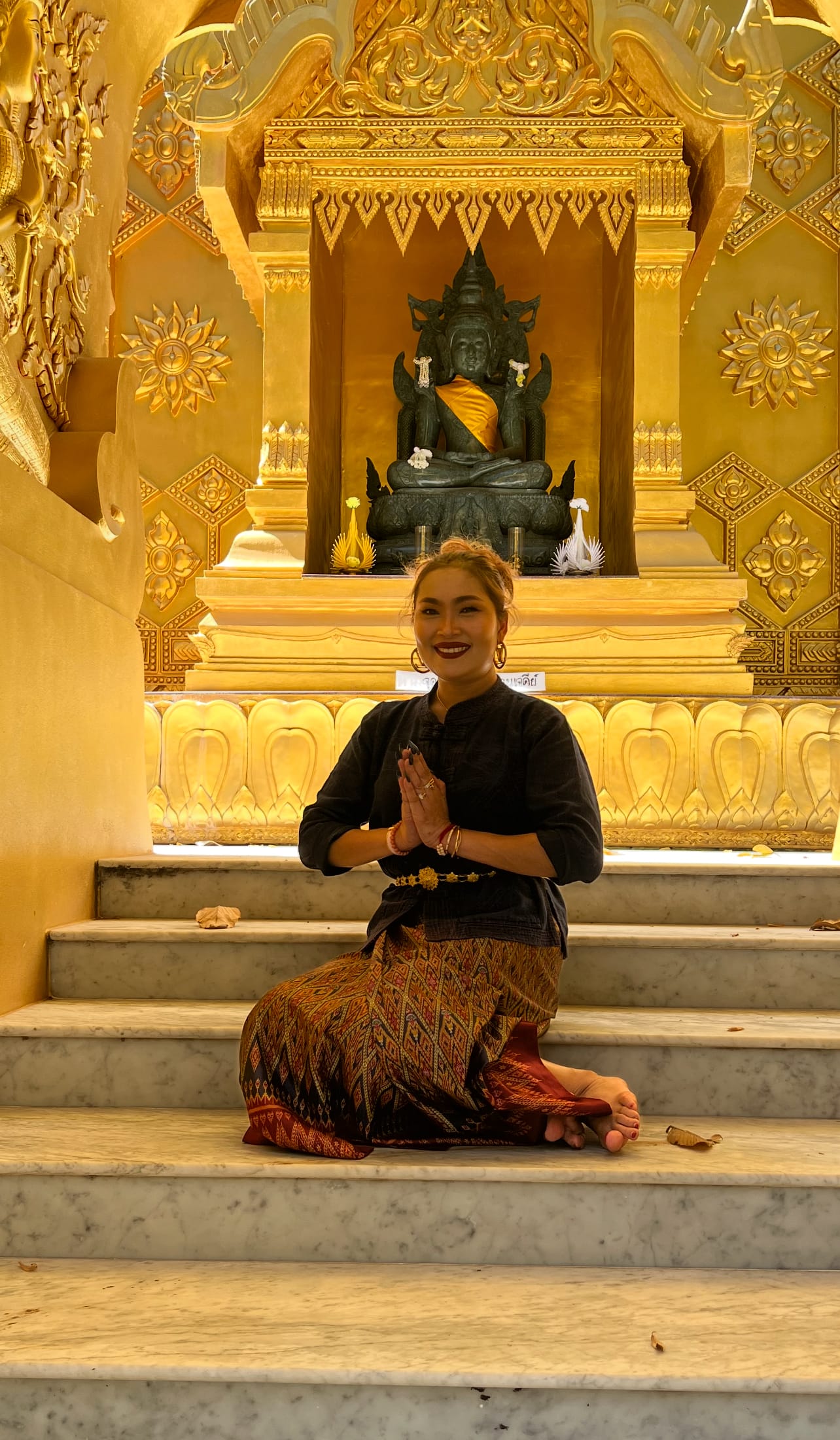 Bee, who runs Lanta Thai Massage, in traditional Thai dress at a golden temple shrine